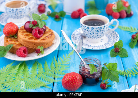 Köstliche Sommer Frühstück, hausgemachte Kuchen und duftenden Kaffee. Auf einem blauen Hintergrund Holz, Beeren und grünen Blättern. Kopieren Sapce. Stockfoto