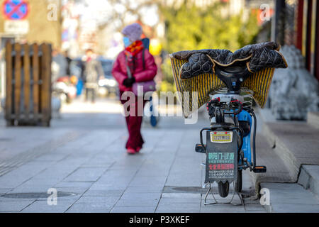 Peking, China - MÄRZ 10, 2016: Leute die Straße entlang. Auf der Straße ist ein geparkten Roller. Stockfoto