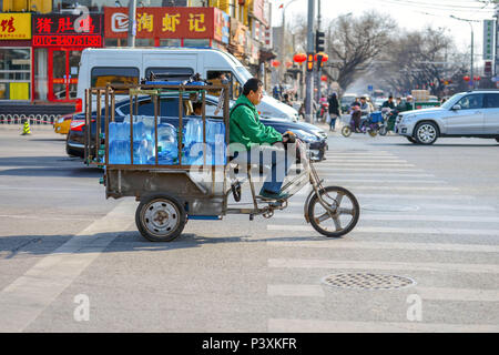 Peking, China - 14. MÄRZ 2016: Leute fahren durch die Straßen mit Fahrrädern, Rollern und Autos. Mit Motorrädern Transport von Menschen, Gütern, Stockfoto