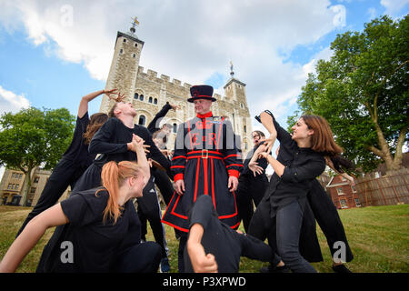 Ein Yeoman Warder, auch bekannt als Beefeater, beobachtet Tänzer, die sich auf die East Wall vorbereiten, unter der Regie von Hofesh Shechter, einem großen Spektakel aus Tanz und Live-Musik, inspiriert von den Gemeinden im Osten Londons, das vom 18. Bis 22. Juli im Tower of London stattfindet. Stockfoto