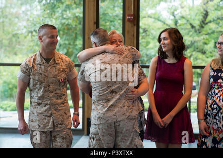 Us Marine Corps Brig. Gen. Christopher Mahoney, Direktor für Strategie und Pläne Division, umarmt Frau Kathleen Goode nach Auftragsvergabe ihr und ihren Töchtern eine Bescheinigung der Anerkennung während Chief Warrant Officer 5 Ruhestand Bradley's Goode Zeremonie an der Semper Fidelis Kapelle, Dreieck, Virginia, 7. Oktober 2016. Goode zog sich nach 26 Jahren des Herrn Abgeordneten und treuen Dienst. (U.S. Marine Corps Foto von Cpl Timothy A. Turner) Stockfoto