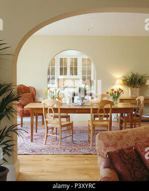 Rush - Sitzen Stühle aus Holz an der langen Holz Tisch im Speisesaal mit Torbögen Stockfoto