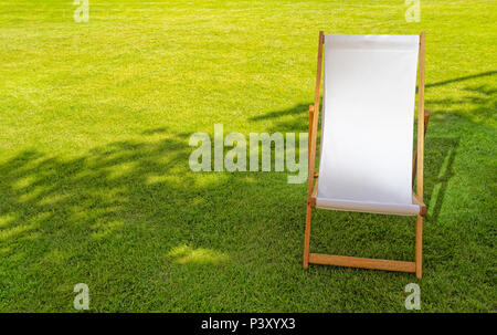 Einzelne weiße Leere Liegestühle auf dem Rasen Stockfoto