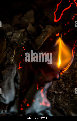 Blatt weißes Papier Brennen in einem Rost mit kleinen Flammen, Rauch und verkohlte Kanten. Stockfoto