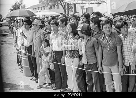 FORT SMITH, AR, Vereinigte Staaten - 10 August 1975 - - die Vietnamesische Flüchtlinge aller Altersgruppen Masse ein Seil Barriere, wie sie für die Ankunft von Präsident Gerald Ford zum Fort Chaffee vietnamesischen Flüchtlingslager warten. Über 20.000 Flüchtlinge waren im Zentrum untergebracht, als Ford Es tourte, kurz nach dem Fall von South Vietnam zu den kommunistischen Norden eine humanitäre Krise, die Evakuierung in Notfällen beendet erstellt. Stockfoto