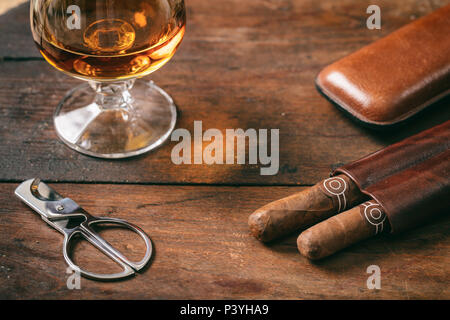 Kubanische Zigarren und ein Glas Cognac auf hölzernen Hintergrund, Detailansicht mit Details Stockfoto