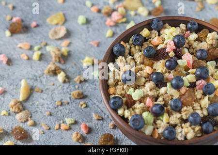 Müsli mit getrockneten Früchten in einem keramischen Platte für ein Frühstück an einem grauen ungleichmäßiger Hintergrund. Stockfoto