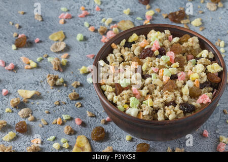 Müsli mit getrockneten Früchten in einem keramischen Platte für ein Frühstück an einem grauen ungleichmäßiger Hintergrund. Stockfoto