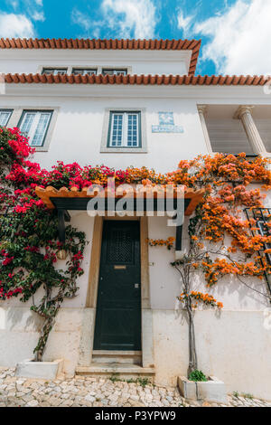 Weitwinkelaufnahme der traditionellen weißen Häusern in der Altstadt von Cascais mit boudaville Pflanzen vor blauem Himmel Stockfoto