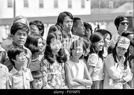 FORT SMITH, AR, USA - 10. August 1975 - Mehrere junge vietnamesische Flüchtlinge Linie ein Abschnitt der Straße und wartet auf die Präsidentschaftswahlen limosine von Gerald Ford als der Präsident kommt, um die Flüchtlinge zu adressieren. Stockfoto