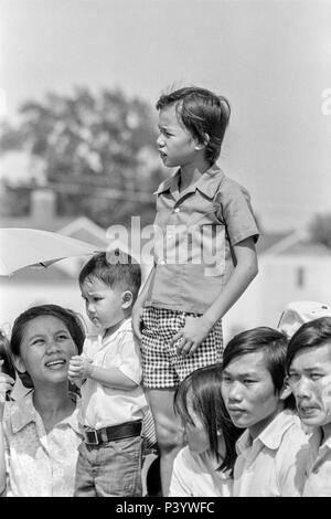 FORT SMITH, AR, USA - 10. AUGUST 1975 -- Neu eingetroffen Vietnamesische Flüchtlinge aller Altersgruppen eine Straße, wo Präsident Gerald Ford zu übergeben. Der Präsident ist zu Besuch in der neuen Vietnamesischen Notaufnahmelager nur am Fort Chaffee, AR geöffnet. Stockfoto