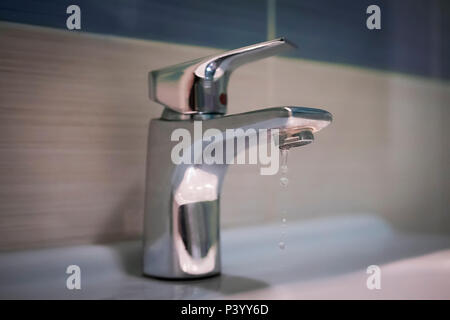 Leitungswasser und Tröpfchen. Edelstahl im Bad. Tropfen Wasser aus dem Wasserhahn. Leckage von Trinkwasser. Ökonomisch nicht Wasser consumpt Stockfoto