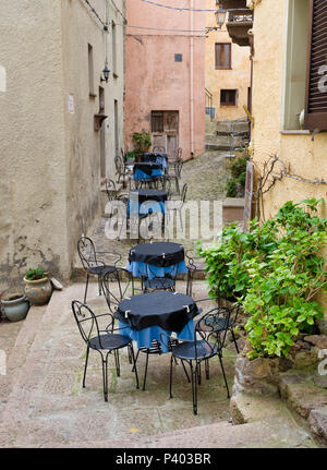 Tabellen mit blauem Tuch und Stühle auf der Terrasse in einer Straße in Castelsardo auf Sardinien Stockfoto