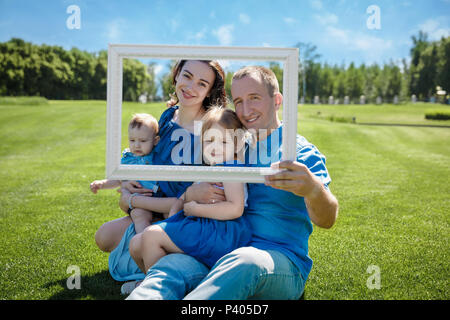 Lächelnd Familie mit Kindern durch einen leeren Rahmen suchen Stockfoto