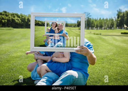 Lächelnd Familie mit Kindern durch einen leeren Rahmen suchen Stockfoto