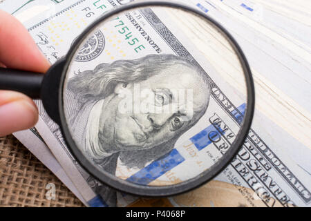 Lupe wird über die Banknote Bündel von US-Dollar gehalten. Stockfoto