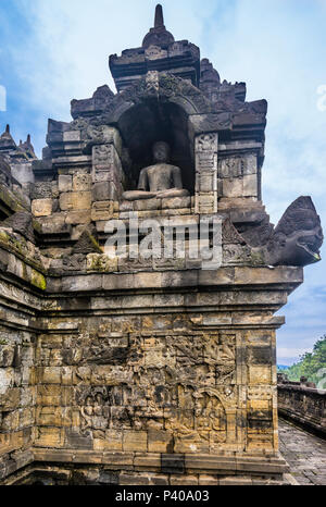 Sitzender Buddha Statue in einer Nische über Reliefs im 9. Jahrhundert Borobudur buddhistischen Tempel, Zentraljava, Indonesien Stockfoto