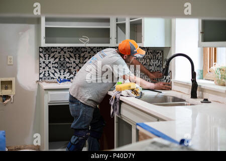 Ein 40 Jahre alter Kaukasischer mann Einbau küche backsplash Fliesen für einen Umbau home Job in Wichita, Kansas, USA. Stockfoto