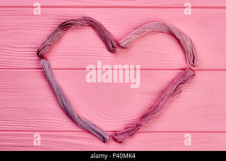 Shape of heart from colorful threads. Pink threads forming heart shape with copy space on wooden background. Threads art design. Stockfoto