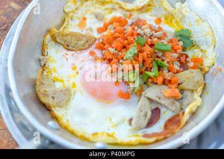 Nordöstliche thailändische Frühstück mit Kaffee, heiße Pfanne Spiegeleier Material mit gehacktem Schweinefleisch und Wurst, auch für Vietnam und Laos Menschen Stockfoto