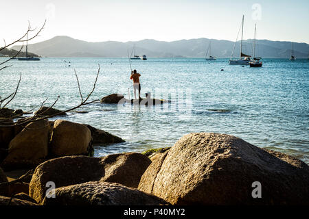 Homem pescando sobre Rocha keine costão rochoso na Praia de Jurerê. Florianópolis, Santa Catarina, Brasilien. Stockfoto