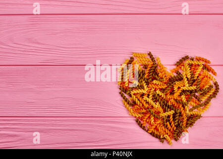 Herz aus Essen auf Holz- Hintergrund. Form des Herzens aus getrockneten Fusilli und Kopieren. Valentines urlaub Grußkarte. Stockfoto