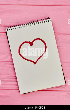 Herz auf Papier notepad erstellt. Bild des Herzens mit Lippenstift auf dem Papier notepad, Ansicht von oben gezeichnet. Symbol der Liebe. Stockfoto