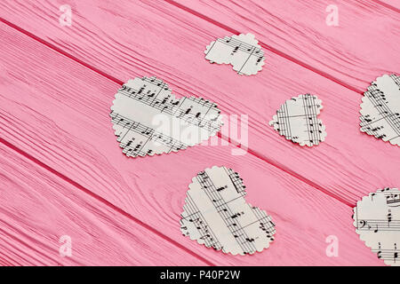 Musik Konzept mit Papier Herzen. Papier Herzen mit Noten auf rosa Holz- Hintergrund. Stockfoto