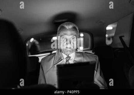 Geschäftsmann mit einem digitalen Tablet auf dem Rücksitz eines Autos sitzen Stockfoto