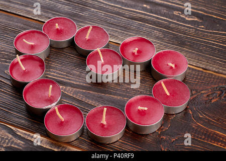 Form des Herzens von Teelicht Kerzen. Wunderschöne Herzform Dekoration von Duftkerzen auf braunem Holz- Hintergrund. Stockfoto