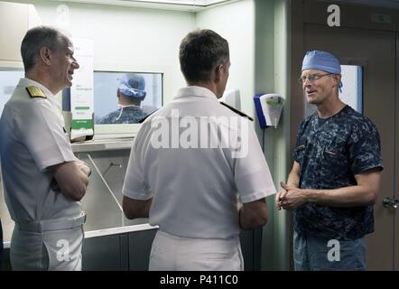 Foto von drei Marine Offiziere, eine getragen surgical Scrubs, sprechen mit jedem anderen an Bord des Hospital Ship USNS Mercy, in den Gewässern vor der Küste von Nha Trang, Vietnam, 23. Mai 2018. () Stockfoto