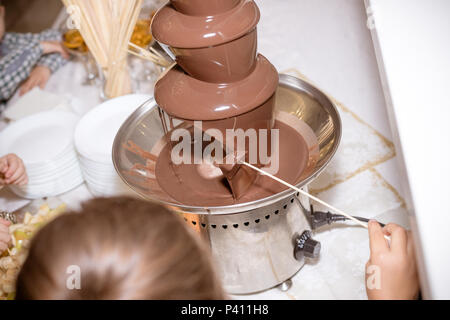 Schokolade Brunnen auf Kindergeburtstag mit einem Zicklein herum spielen und Marshmallows und Früchte dip Eintauchen in Brunnen. Schokolade Brunnen und Obst zum Nachtisch Stockfoto