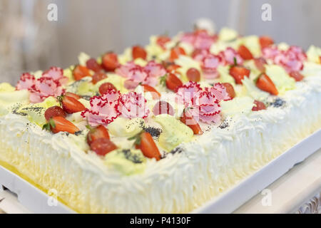 Strawberry meringue Kuchen auf einem Tisch auf grauem Hintergrund. Kuchen mit Früchten. Selektive konzentrieren. Sahne und Joghurt Kuchen mit frischem Obst auf dem Tisch mit Tischdecke, rustikal Stil. Stockfoto