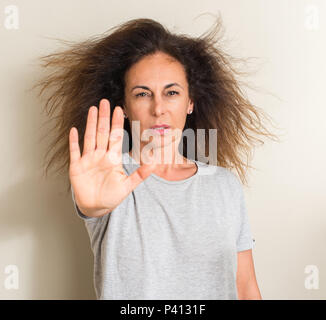 Gewelltes Haar Brasilianerin mit offener Hand das STOP-Schild mit ernsten und selbstbewussten Ausdruck, Verteidigung Geste Stockfoto