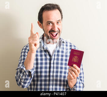 Älterer Mann mit spanischen Reisepass mit einer Idee oder Frage Zeigefinger mit glücklichen Gesicht überrascht, Nummer eins Stockfoto