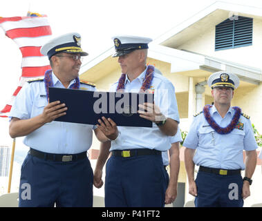 Hintere Adm. Vincent Atkins, Commander, Coast Guard 14. Bezirk, präsentiert eine Auszeichnung der Master Chief Petty Officer Christopher Windnagle während eines Change-of-watch und Ruhestand Zeremonie an der Coast Guard Base Honolulu Juni 1, 2016. Während der Zeremonie, Master Chief Petty Officer Chritopher Windnagle übertragene Autorität als command Master Chief der Küstenwache 14. Bezirk zu Master Chief Petty Officer Edward Lewis. (U.S. Coast Guard Foto von Petty Officer 2. Klasse Tara Molle/Freigegeben) Stockfoto