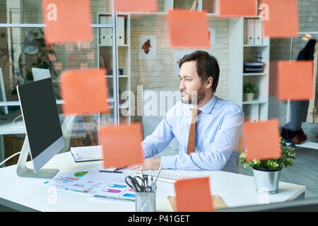 Mann im Büro hinter Glas arbeiten Stockfoto
