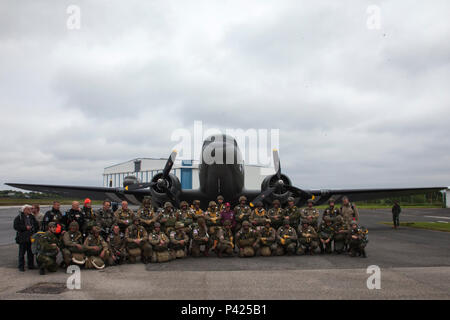 Mitgliedern des runden Vordach Fallschirmspringen Team und Fallschirmjäger aus der Luftlandebrigade 1 posieren für ein Foto vor Fallschirmspringen in Fresville, Frankreich, 2. Juni 2016. Die runde Vordach Fallschirmspringen Team führt den Zweiten Weltkrieg Stil fallschirmspringen Tätigkeiten der Speicher der Fallschirmjäger, die kämpften, Europa und ihren selbstlosen Opfer zu befreien zu verstärken. (U.S. Armee Foto von SPC. Joseph Cathey/Freigegeben) Stockfoto