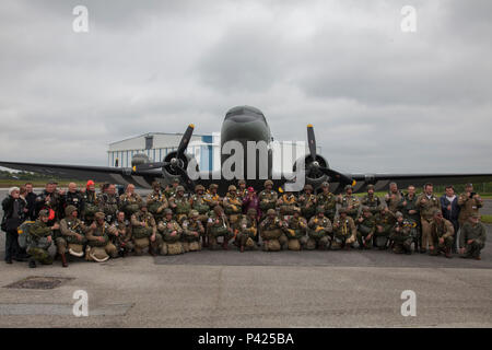 Mitgliedern des runden Vordach Fallschirmspringen Team und Fallschirmjäger aus der Luftlandebrigade 1 posieren für ein Foto vor Fallschirmspringen in Fresville, Frankreich, 2. Juni 2016. Die runde Vordach Fallschirmspringen Team führt den Zweiten Weltkrieg Stil fallschirmspringen Tätigkeiten der Speicher der Fallschirmjäger, die kämpften, Europa und ihren selbstlosen Opfer zu befreien zu verstärken. (U.S. Armee Foto von SPC. Joseph Cathey/Freigegeben) Stockfoto