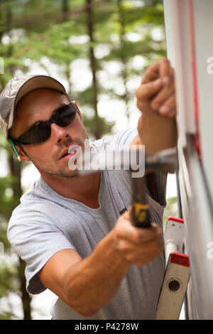 Ein Bauarbeiter hämmerten einen Nagel Vinylabstellgleis in Ontario, Kanada zu sichern. Stockfoto