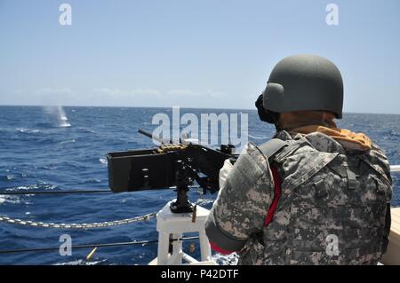 Ein Crew-Mitglied an Bord des Küstenwache Cutter Heriberto Hernandez feuert ein Maschinengewehr des Kalibers .50 während Tradewinds 2016, einer multinationalen Karibikübung. Die Operation verbessert die Sicherheit im Seeverkehr, die Fähigkeiten der Kanonenschießen, die Interoperabilität, die Bekämpfung der organisierten Kriminalität, die Katastrophenbewältigung, und humanitäre Hilfe in Abstimmung mit dem US-Südkommando und den Partnerländern. Stockfoto