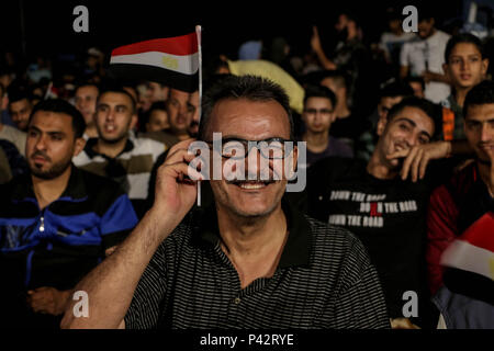 Ein palästinensischer Mann der Flagge Ägypten während und beobachten, wie die ägyptische Mannschaft bei der WM in der Hafens von Gaza. Die Palästinenser auf einem großen Bildschirm die Russland 2018 World Cup Gruppe ein Fußballspiel zwischen Russland und Ägypten im Seaport in Gaza Stadt. Russland gewann 3-1. Stockfoto