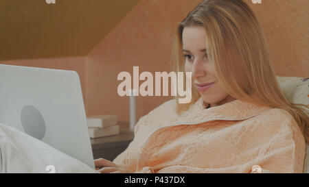 Volle Länge seitliche Ansicht der weiblichen Patienten mit Laptop auf dem Bett im Krankenhaus Stockfoto