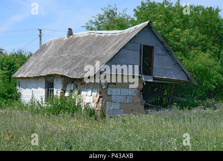 Verlassene kleine ländliche Hütte mit völlig ruiniert Ecke in hellen Sommer Sonnenlicht in der Ukraine. Stockfoto