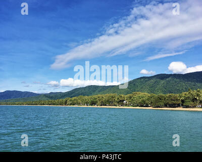 Am Morgen idyllische Winter Blick auf entspannende Palm Cove Beach, offshore Onshore-, die Palmen dann den Regenwald bedeckten Hügeln Stockfoto