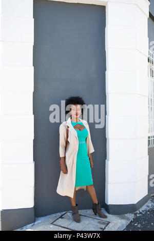 Eine afrikanische Frau Modell stellt neben eine dunkel kontrastiert Wand Stockfoto