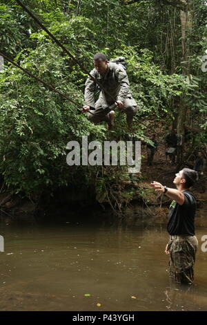 U.S. Army Staff Sgt. Larry Aviles, Jungle Operations Training Center Instructor mit rasender Akademie, Sitz und Hauptverwaltung Bataillon, 25 Infanterie Division, fördert die US-Armee Soldat Bravo Co 3 Bataillon zugeordnet, 7 Infanterie Regiment, 2 Infantry Brigade Combat Team, 3rd Infantry Division, als er die letzten Kabel Hindernis bei der team Hindernisparcours Kreuze an der Französischen Jungle Warfare School in Gabun, 10. Juni 2016. Soldaten an der Französischen Jungle Warfare Schule als Teil der US-Armee Afrika übung Zentrale Accord 2016, eine jährliche, kombiniert, gemeinsame militärische Stockfoto