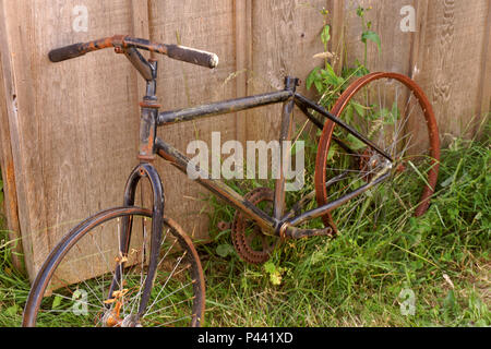 Rostiges Fahrrad lehnte sich gegen einen Holzzaun Stockfoto