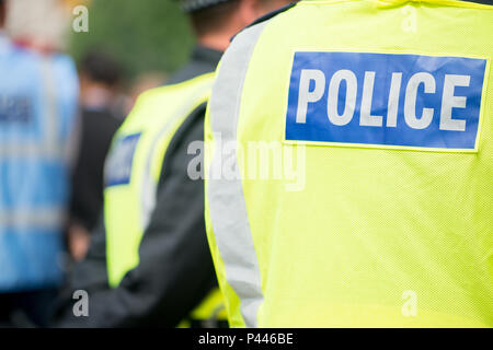 Großstadtpolizisten tragen eine Visierweste mit POLIZEIAUFDRUCK auf der Rückseite, während sie in London, Großbritannien im Einsatz sind. Stockfoto