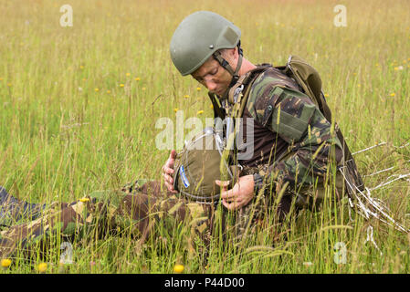 Eine niederländische Armee Fallschirmjäger prüft seine Ausrüstung nach dem Springen in Bunker Drop Zone in Grafenwöhr, Deutschland, 15. Juni 2016, während der Übung die schnelle Reaktion 16. Übung schnelle Reaktion ist eines der führenden militärischen Krisenreaktion Schulungen für multi-nationale zerstreuten Kräfte in der Welt. Die Übung ist so konzipiert, dass die Bereitschaft der Bekämpfung der Kern der U.S. Global Response Force - derzeit der 82nd Airborne Division 1st Brigade Combat Team - Schnelle-Antwort, Joint-gewaltsamen Eindringen und neben hoher Einsatzbereitschaft der Alliierten Streitkräfte in Europa zu verbessern. Swift Respons Stockfoto